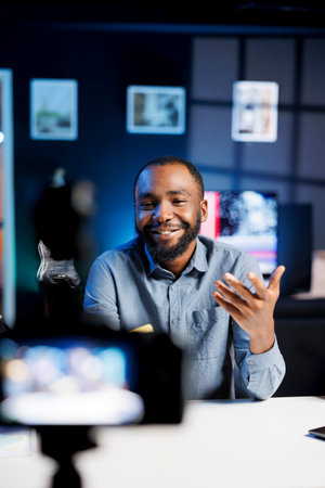 Smiling content creator using professional recording camera and microphone to do livestream and talk with fans. Online streamer using video production gear to do live broadcast for his subscribersの写真素材