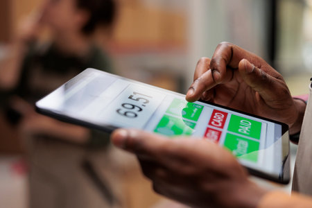 Employee analyzing customers online orders using tablet computer, preparing cardboard boxes for delivery. African american storage room supervisor working at products inventory in warehouse. Close upの写真素材