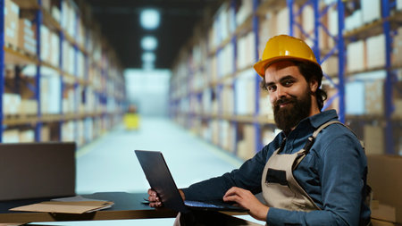 Shipment operations officer uses laptop to confirm stock and superior quality of each product within the package. Staff member checks shipping tags at import export facility, creates dispatch note.の写真素材