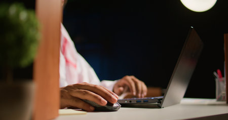Close up shot of hardworking businessman using laptop keyboard and mouse at office desk to surf the...