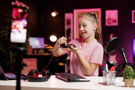 Generation Z online star in studio reviewing gaming mouse in front of professional camera in studio. Smiling kid filming electronics haul, showcasing wired RGB lit computer peripheral to audienceの写真素材