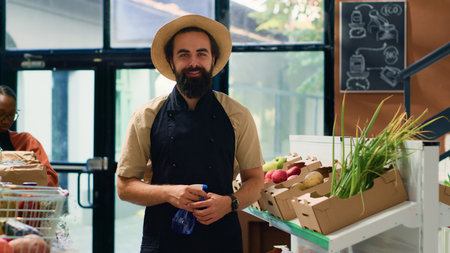 Small business owner in zero waste store arranging organic products on shelves, preparing local fresh produce market for shopping. Man growing fruits and vegetables, ethically sourced.の写真素材