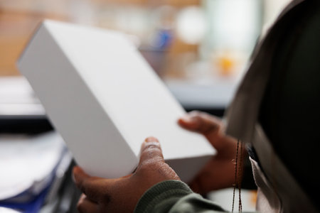 Stockroom employee holding white cardboard boxes, checking products before shipping packages in...