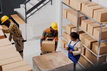 Afrian american package handlers packing parcel and checking order before delivery. All black...