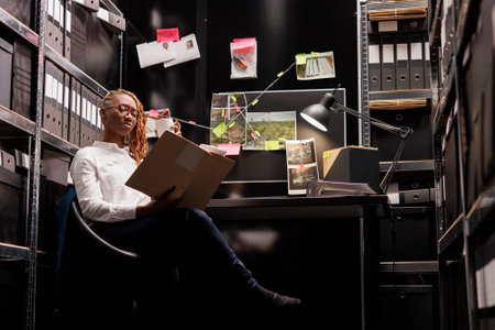 Woman police investigator studying csi expertise report in office. African american policewoman...