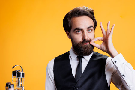 Confidential person does hush mute sign on camera, showing sealed lips gesture with hand. Professional employee at restaurant doing silence symbol, private man in suit and tie.の写真素材