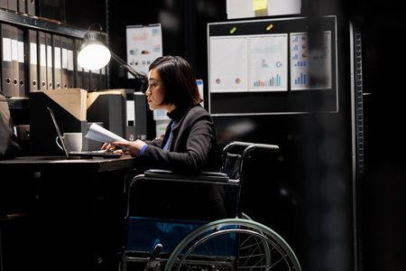 Paralyzed businesswoman employee in wheelchair checking bookkeeping analytical data documents. Accountant with disability in business company file cabinet depository filled with charts and foldersの写真素材
