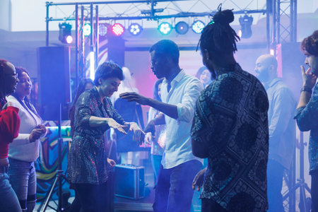 Cheerful dancers doing dance battle while having fun and partying with friends in nightclub. Smiling...
