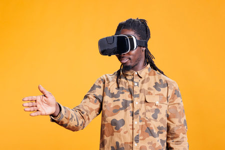Confident person using virtual reality goggles, enjoying playing with virtual reality glasses to see 3d visual simulation. African american man wearing modern goggles to use futuristic technology.の写真素材