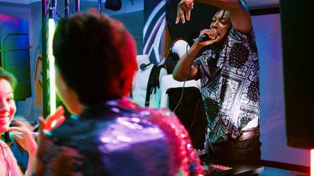 Modern adults attending party with DJ, dancing and jumping around in nightclub. Diverse group of friends partying together on electronic music at event, entertainment. Handheld shot.の写真素材