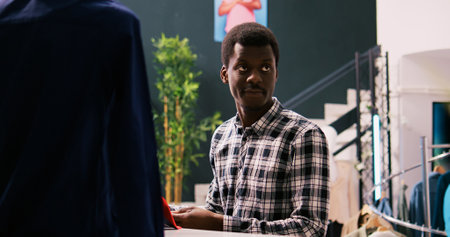 Portrait of customer smiling during shopping session, analyzing elegant tie in modern boutique. African american man shopping for stylish merchandise and trendy accessories in clothing storeの写真素材