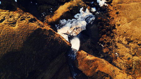 Arctic cascade falling down off cliff, foss a sidu waterfall with river flow running off frozen hills in icelandic landscape. Spectacular water stream in nordic nature and wilderness. Aerial view.の写真素材