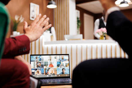 Two employees using videocall remote while they wait for room to be ready, attending business meeting teleconference. Entrepreneur talking to colleagues in hotel lobby, telework.の写真素材