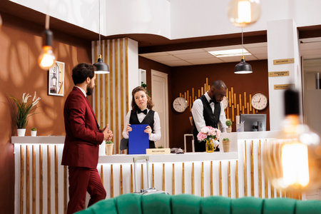 Hotel concierge greet client at reception, providing luxury accommodation services. Businessman finishes check in process, marking the beginning of business trip and preparing for productive stay.の写真素材