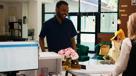 African american guest receiving luxury service upon his arrival at tropical seaside resort, receptionist welcoming tourist at front desk. Man with trolley bags doing check in process. Handheld shot.の写真素材