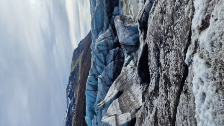 Glacier hiking vatnajokull ice cap in iceland with freezing cold icy blocks on scandinavian big lake, icelandic landscape. Majestic arctic icebergs near brown frosty hills and snowy fields.の写真素材