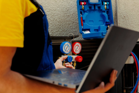 Close up of capable electrician calibrating ac gauges vacuum pump during comissioned hvac system troubleshooting. Seasoned wireman looking for potential low pressure in condenser cooling systemの写真素材