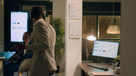 Employee enjoying music at work, bored of checking financial data charts on computer. Staff member...