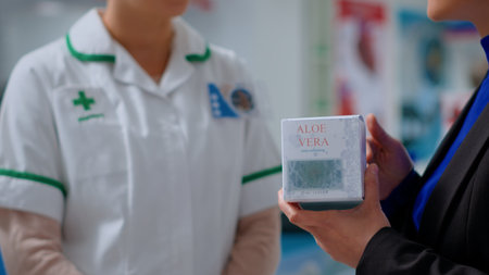 Close up of qualified pharmacist in dispensary offering shopper aloe vera product for treating sun burns. Healthcare professional in chemist store helping client with pain calming balmの写真素材