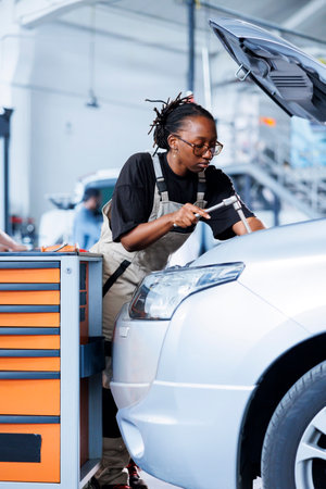 Engineer in car service use torque wrench to tighten bolts after replacing engine. African american...