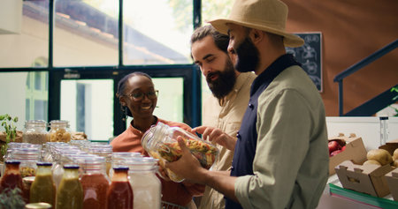 Seller shows ripe fruits and veggies to clients going grocery shopping, diverse people choosing potatoes and other food items for healthy nutrition. Local bio market vendor recommending products.の写真素材