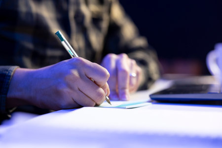 Selective focus on person writing on notepad at table, studying and researching of information....