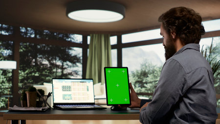 Executive director looks at greenscreen display on tablet, working with latest technology to invest...