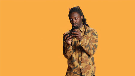 African american man having fun with mobile videogames on smartphone app, playing shooter competition over orange background. Joyful player enjoying gaming challenge on camera.の写真素材