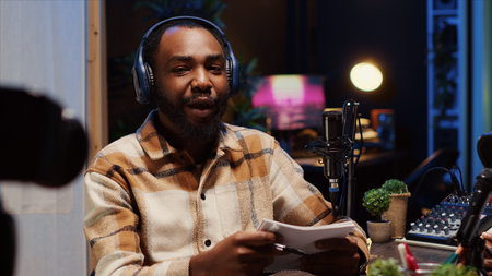 Man on podcast using recording camera while talking with guest during marathon streaming live broadcast for good humanitarian cause, gathering donations from viewers, filming with professional gearの写真素材