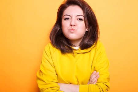 Confident beauty model with brunette hair makes a kissy face on camera while posing carefree in the...