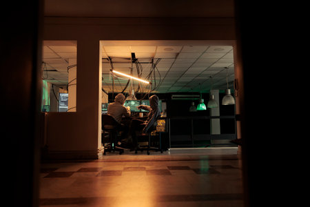 Diverse team of thieves coding trojan virus late at night, hacking computer system with malware. Young hackers planning to crack server, looking to steal passwords, malicious software.の写真素材