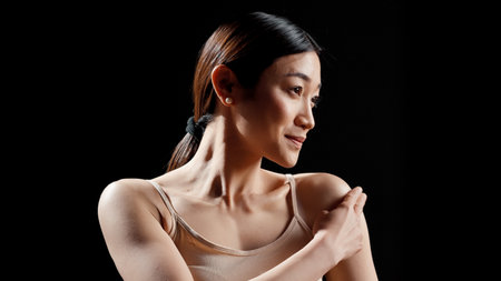 Radiant happy girl applying moisturizer on shoulders, promoting bodycare and body acceptance on camera. Young glowing adult creating ad campaign for cosmetics in skincare routine.の写真素材