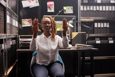 African american woman police detective using ar to visualize crime case information. Law enforcement investigator making arm gestures while brainstorming with augmented reality technologyの写真素材