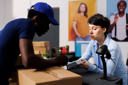 Caucasian manager signing logistics files, discussing delivery details with courier in clothing store. African american deliveryman preparing to ship customers online orders in modern boutiqueの写真素材