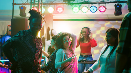 Male dancer having fun at club, doing funky dance moves on dance floor packed with people....