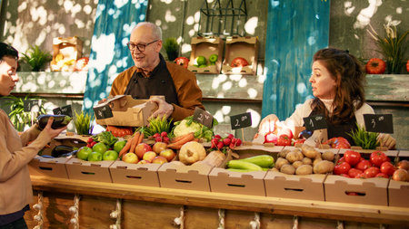 Vegetarian couple shopping at local farmers market on sunny day. Young man and woman standing at local produce counter looking at various locally grown organic fruits and vegetables.の写真素材