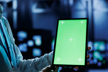 Dara center system administrator running code and programming on mockup tablet, troubleshooting and upgrading high tech workplace designed to accommodate rows of fully operational servers, close upの写真素材