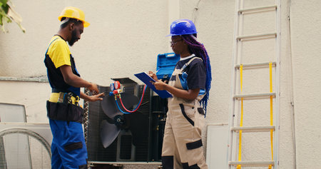 Diverse team of capable electricians brainstorming possible ways to repair damaged outdoor hvac...