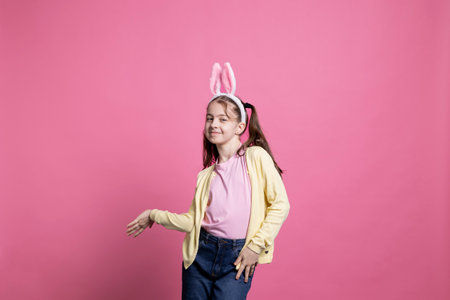 Joyful toddler with pigtails and bunny ears dancing on camera, showing cute dance moves and fooling...