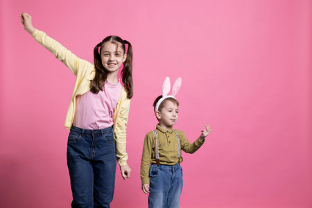 Happy young siblings dancing around being funny in studio, feeling joyful and excited about easter...