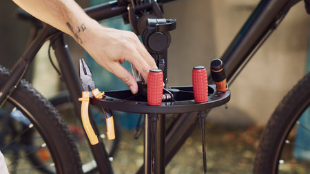 Close-up glimpse of finely-tuned tools carefully being arranged on repair stand waiting for bicycle maintenance activities to take place. Man organizing equipment for bike servicing.の写真素材