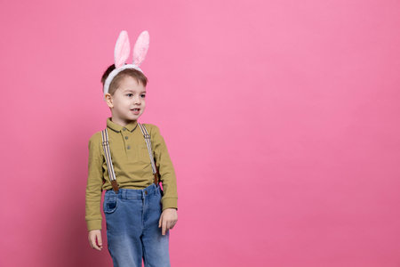 Little boy being cute with bunny ears in front of the camera, feeling excited about easter...