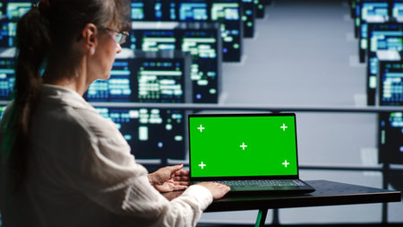 Proficient system administrator in server farm housing high end rackmounts capable of quickly and efficiently performing complex computations and data analysis, using mockup laptop to prevent crashesの写真素材