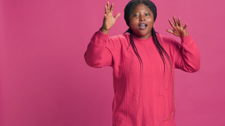 Young black woman displeased and saying no at camera with hands raised. African american fashion blogger having disappointed self expression positioned against pink background.の写真素材