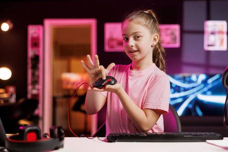 Happy young girl in studio reviewing gaming mouse in front of camera in personal studio. Cheerful...