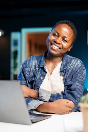 Portrait of african american lady flashing a genuine smile while sitting in front of her portable...