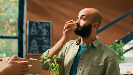 Storekeeper gives fresh lemons to man to smell and enjoy organic natural citrus scent, buying locally grown fruits from grocery store vendor. Adult supporting local small business. Handheld shot.の写真素材