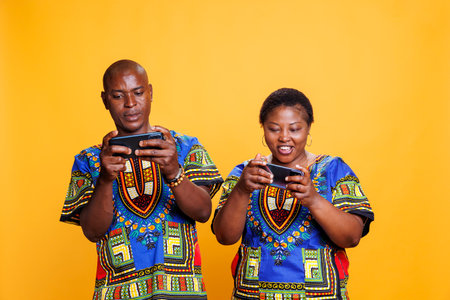 Happy couple in relationship with cheerful expression enjoying online game on mobile phones. Smiling...