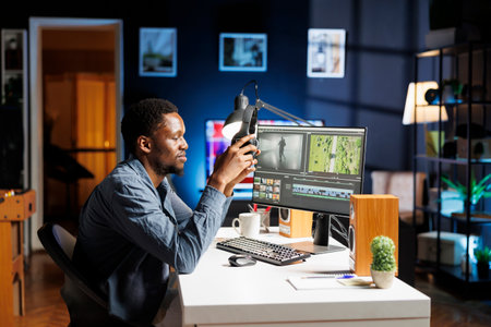 Video editor working on montage clip edit at night, using color grading software on pc at workstation. Young adult videographer working as designer with lights and white balance.の写真素材