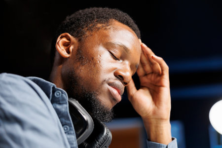 Self employed person feeling fatigued at home desk, yawning and trying to focus on solving tasks and meeting deadline. Young adult working on new contract, experiencing burnout.の写真素材